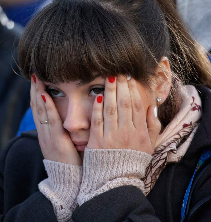 A fan covers her face while watching the men’s ice hockey game between Russia and Finland on a large screen in Olympic Park, at the 2014 Winter Olympics, Feb. 19, 2014, in Sochi, Russia. (Photo credit: AP Photo/Morry Gash)