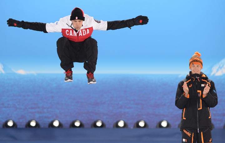 A picture taken with a robotic camera shows (from L) Canada’s silver medalist Denny Morrison jumping next to Netherlands’ gold medalist Stefan Groothuis during the Men’s Speed Skating 1000 m Medal Ceremony at the Sochi medals plaza during the Sochi Winter Olympics on February 13, 2014. (Antonin Thuillier/AFP/Getty Images)