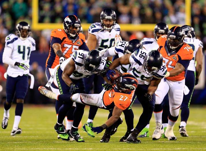 Running back Knowshon Moreno of the Denver Broncos is tackled by defensive end Chris Clemons, defensive end Cliff Avril and middle linebacker Bobby Wagner of the Seattle Seahawks in the first quarter during Super Bowl XLVIII at MetLife Stadium on February 2, 2014 in East Rutherford, New Jersey. (Rob Carr/Getty Images)