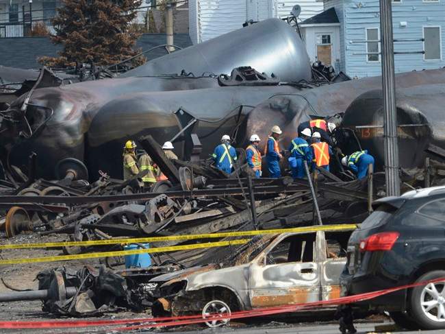 In this July 6, 2013 file-pool photo, emergency workers examine the aftermath of a train derailment and fire in Lac-Megantic, Quebec.