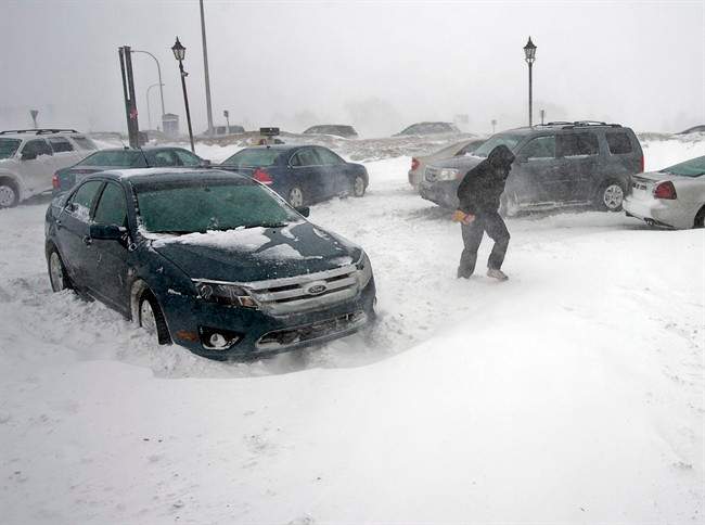 A stranded traveller crosses a parking lot at a service station in Borden-Carleton, Prince Edward Island on Sunday, Feb. 16, 2014.