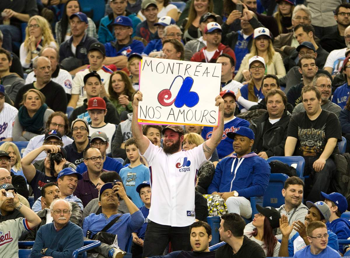 Fans wear Montreal Expos uniforms as they watch the Toronto Blue Jays in a pre-season baseball game against the New York Mets .