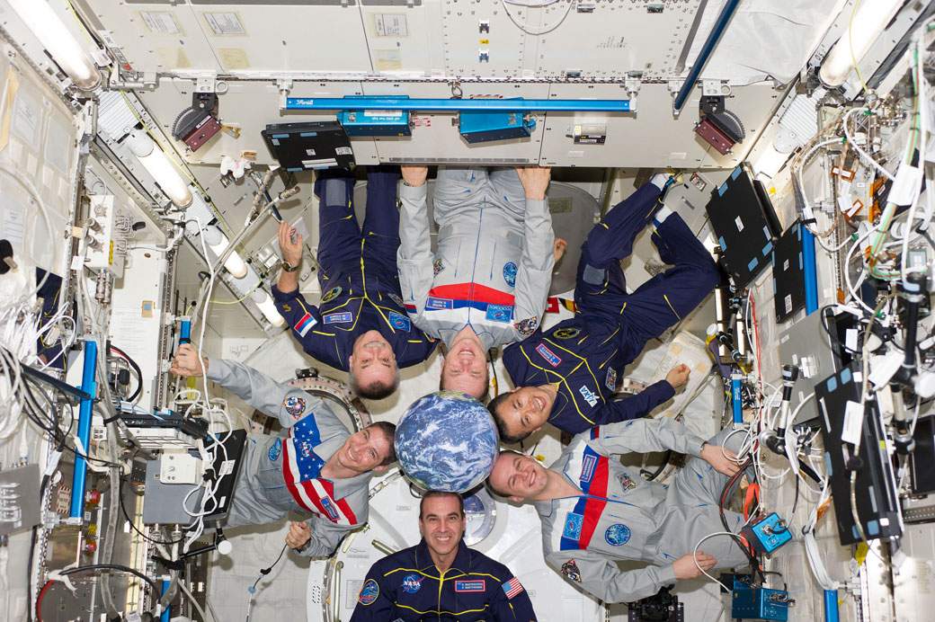 One big, happy family. Expedition Crew 38, gather around a not-so-life-sized orb of Earth.