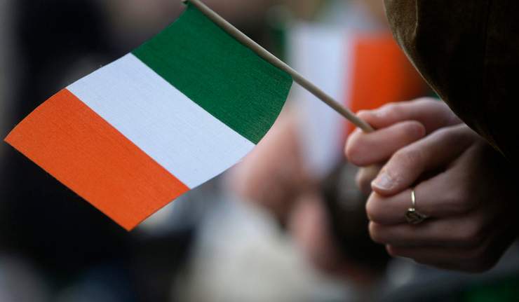A reveler holds an Irish flag while attending a St. Patrick's Day parade.