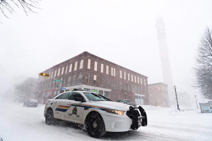 An RCMP cruiser drives along Main street with the Bell Aliant tower in the background barely visible due to blowing snow and high winds in Moncton, N.B., Wednesday, March 26, 2014.