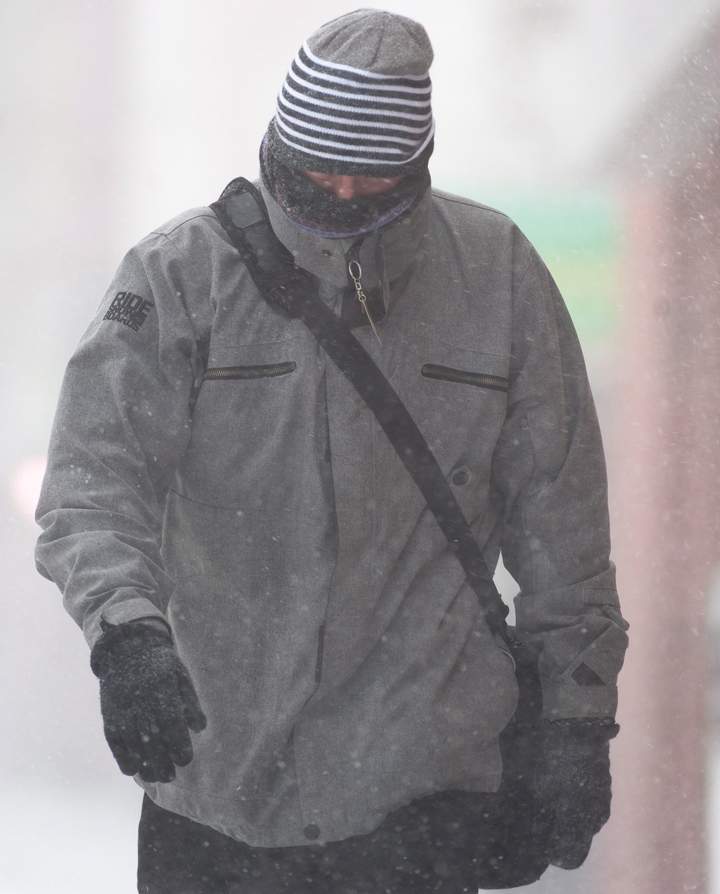 A man walks along Main Street battling high winds and whiteout conditions during a spring storm in Moncton, N.B., Wednesday, March 26, 2014.