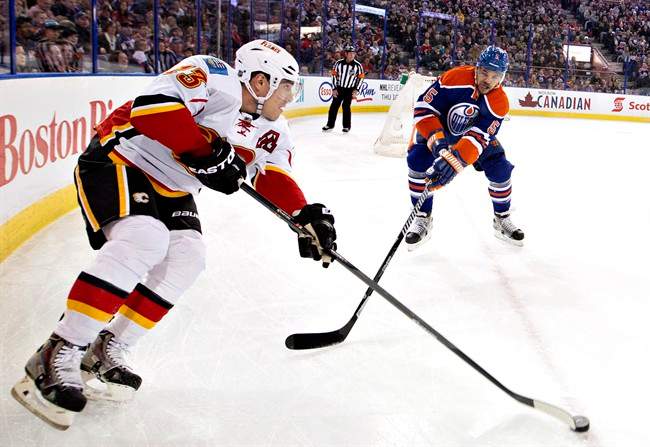 Calgary Flames' Sean Monahan (23) battles in the corner with Edmonton Oilers' Mark Fraser (5) during first period NHL hockey action in Edmonton, Alta., on Saturday March 1, 2014.