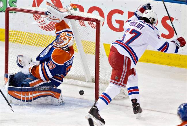 New York Rangers Benoit Pouliot (67) celebrates as the puck goes past Edmonton Oilers Ben Scrivens (30) during second period NHL hockey action in Edmonton, Alta., on Sunday March 30, 2014. THE CANADIAN PRESS/Jason Franson.