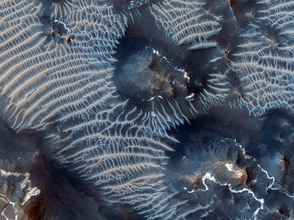 High on the Tharsis rise in the upper parts of the Valles Marineris canyon, windblown sediments create this image of contrasts.