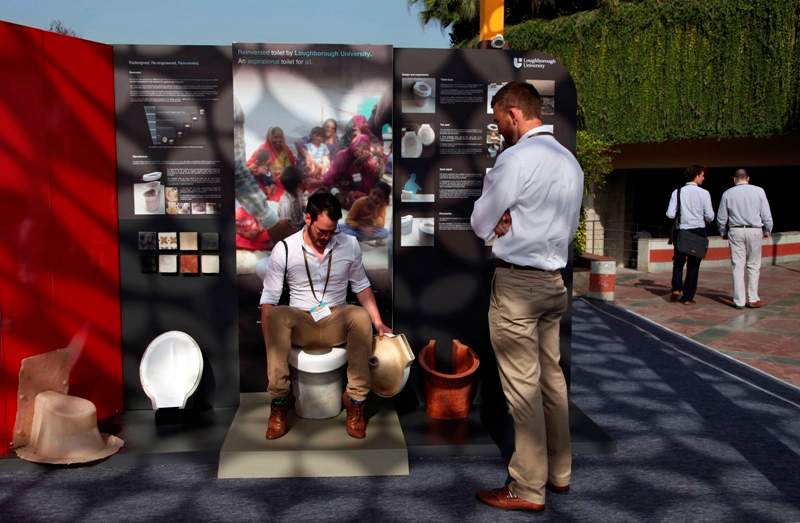 In this Friday, March 21, 2014 photo, an exhibitor from Loughborough University demonstrates the use of a toilet during Reinvent The Toilet Fair in New Delhi, India. Scientists who accepted the Bill & Melinda Gates Foundation’s challenge to reinvent the toilet showcased their inventions in the Indian capital Saturday. (AP Photo/Tsering Topgyal).