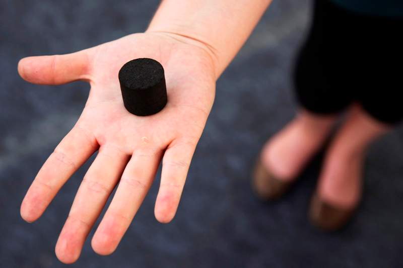 In this Friday, March 21, 2014 photo, an exhibitor displays a Biochar, a charcoal-like product made from human waste, used as cooking fuel or fertilizer, at the Reinvent The Toilet Fair in New Delhi, India. (AP Photo/Tsering Topgyal)