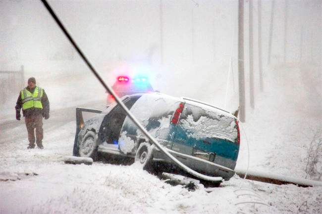 Grant County Sheriff's officers stand by at the scene of an accident on Ind. 26 east of Upland, Ind., as snow falls Wednesday, March 12, 2014.