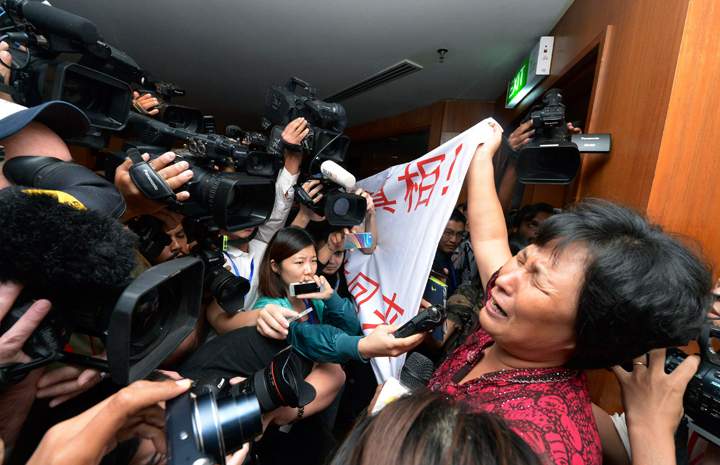 A Chinese relative of passengers aboard a missing Malaysia Airlines plane cries as she holds a banner in front of journalists reading ‘We are against the Malaysian government for hiding the truth and delaying the rescue. Release our families unconditionally!” at a hotel in Sepang, Malaysia.