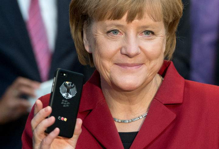 German Chancellor Angela Merkel holds a tapping proof BlackBerry mobile device at the stand of Secusmart as she tours the CeBIT high-tech fair during the opening event of the world’s largest computer expo on March 5, 2013 in Hanover