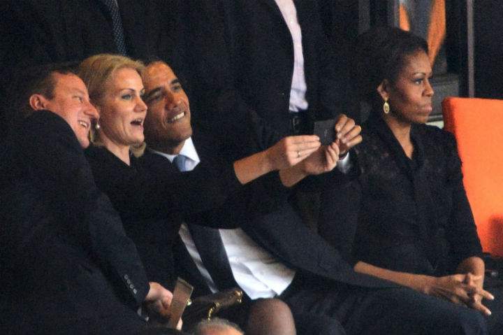 US President Barack Obama (R) and British Prime Minister David Cameron pose for a selfie picture with Denmark’s Prime Minister Helle Thorning Schmidt (C) next to US First Lady Michelle Obama (R) during the memorial service of South African former president Nelson Mandela at the FNB Stadium (Soccer City) in Johannesburg on December 10, 2013.