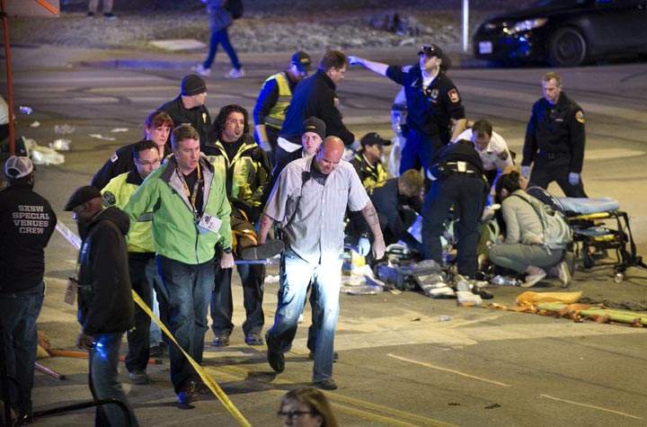 People carry a person who was struck by a car on Red River Street in downtown Austin, Texas, at SXSW on Wednesday March 12, 2014. (AP Photo/Austin American-Statesman/ Jay Janner)