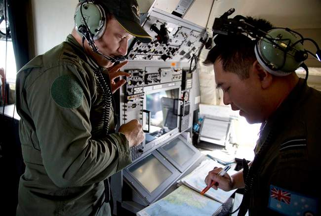 Crew members aboard a Royal Australian Air Force AP-3C Orion aircraft observe navigation maps as they search for missing Malaysian Airlines flight MH370 over the southern Indian Ocean, Thursday, March 27, 2014.