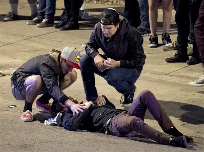 Bystanders tend to a man who was struck by a vehicle on Red River Street in downtown Austin, Texas, on Wednesday March 12, 2014. Police say two people were confirmed dead at the scene after a car drove through temporary barricades set up for the South By Southwest festival and struck a crowd of pedestrians. (AP Photo/Austin American-Statesman, Jay Janner).