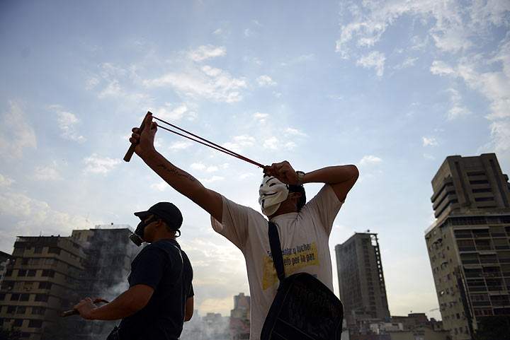 An opposition activist throws stones at the national police during a protest against the government of Venezuelan President Nicolas Maduro, in Caracas on March 10, 2014.