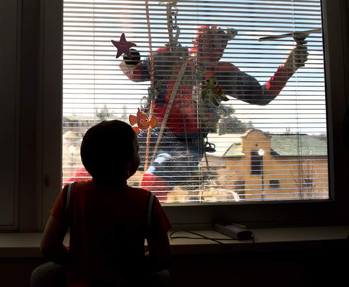 A young patient in the Paediatric Ward watches from his room as a window washer in a Spiderman costume washes the windows at Lakeridge Health in Oshawa, Ontario, on Friday, March 21, 2014.