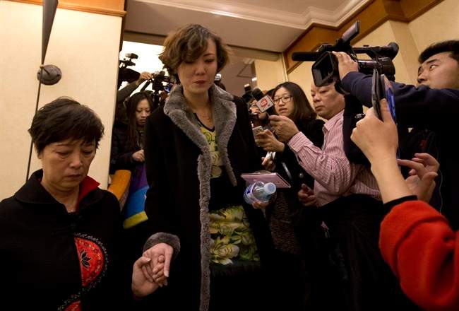 Chinese women, relatives of passengers aboard a missing plane, walk past the media outside a room at a hotel in Beijing, China Saturday, March 8, 2014.