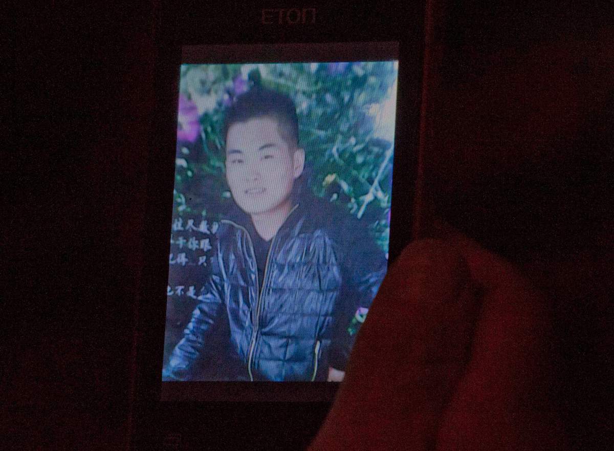Xie Xincui holds a mobile phone showing a photo of her son Feng Dong, a passenger on board the Malaysia Airlines Flight 370 at a hotel where relatives gather to wait for news of the missing plane in Beijing, China, Tuesday, April 8, 2014.