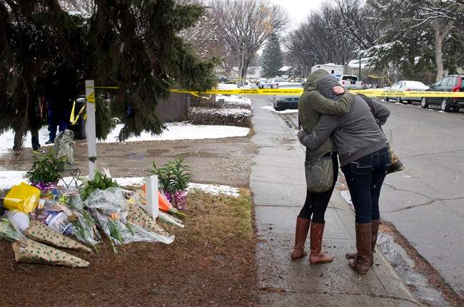 Women cry and hug beside a makeshift memorial near the scene of the multiple fatal stabbings in northwest Calgary on Wednesday, April 16, 2014. 