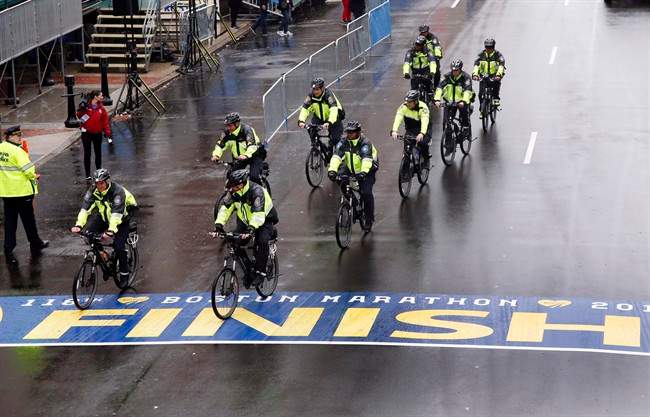 Police on bikes cycle across the Boston Marathon finish line prior to a remembrance ceremony for family members and survivors of the 2013 Boston Marathon bombing on Boylston Street in Boston, Tuesday, April 15, 2014.