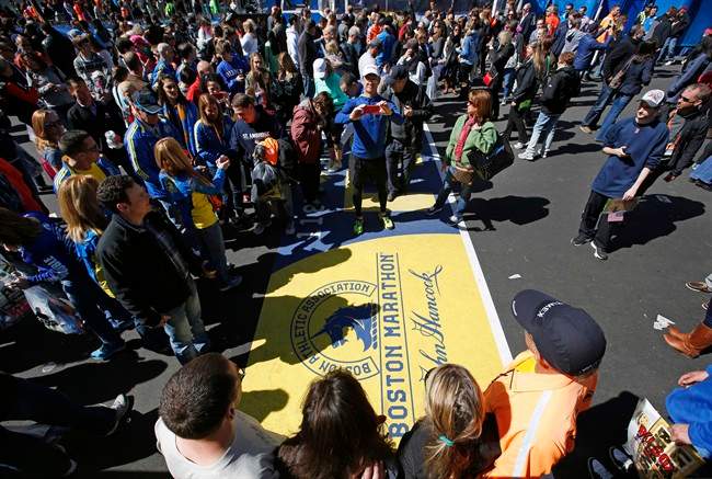 A large crowd gathers to pose for photos at the Boston Marathon finish line, one day before the race, Sunday, April 20, 2014, in Boston.