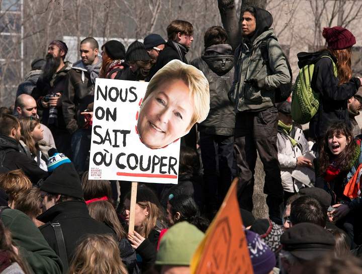 A protester holds a sihn reading "We know where to Cut" with a photo of Quebec Premier Pauline Marois during a against anti-austerity measures Thursday, April 3, 2014 in Montreal.