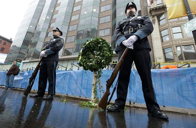 Police officers guard a memorial wreath at the site of the first bomb explosion near the finish line of the Boston Marathon, Tuesday, April 15, 2014, in Boston.