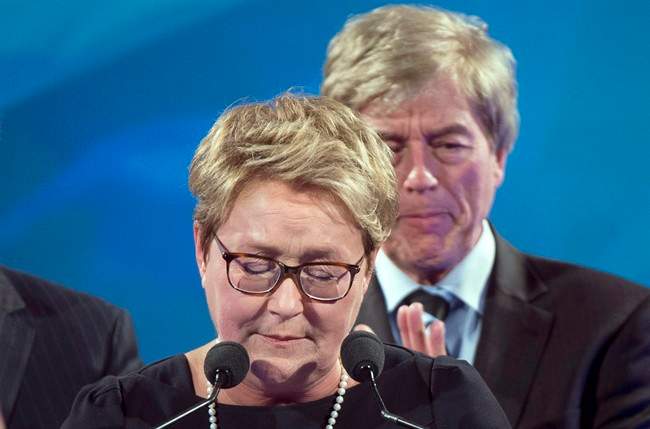 PQ leader Pauline Marois pauses during her speech as her husband Claude Blanchet (rear) applauds at the party's election headquarters Monday, April 7, 2014 in Montreal.