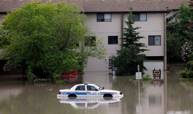 A police car sits stuck in a parking lot of an apartment building after heavy rains have caused flooding, closed roads, and forced evacuations in Calgary, Alta., Friday, June 21, 2013. THE CANADIAN PRESS/Jeff McIntosh