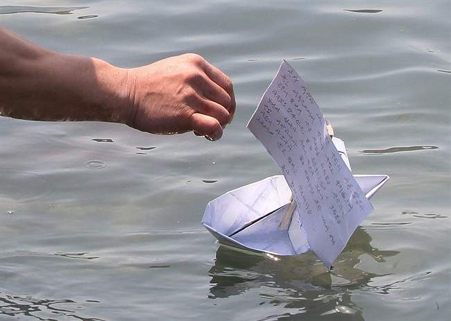 A relative of a passenger releases a paper boat with a message wishing for the safe return of his missing loved one.