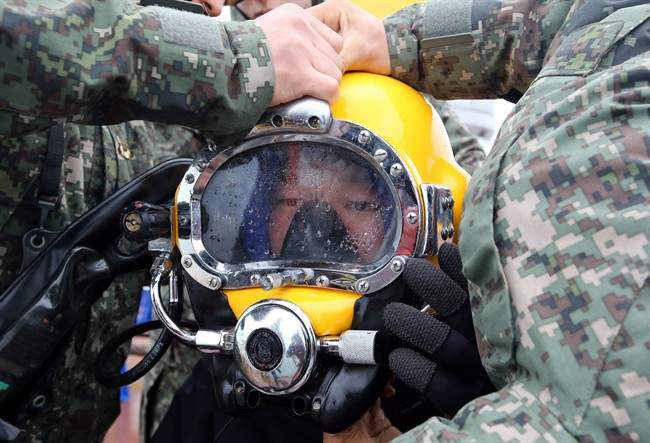 A diver wears a helmet to look for people still missing from the sunken ferry Sewol, in the water off the southern coast near Jindo, South Korea, Saturday, April 26, 2014.