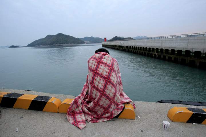 A relative waits for their missing loved one at a port.