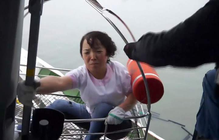 In this image made from video from South Korean Coast Guard, a passenger is rescued and hoisted onto a Coast Guard helicopter.