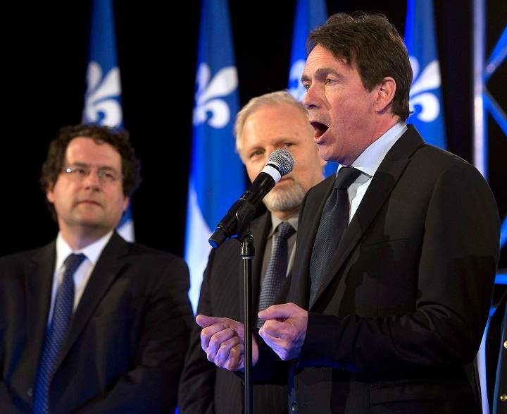 Parti Quebecois newly elected MNA Pierre Karl Peladeau, right, speaks to supporters as Ministers Bernard Drainville, left, and Jean-Francois Lisee look on Monday, April 7, 2014 in Montreal.