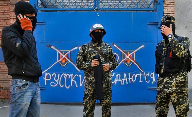 Pro Russian militants stand in front of a gate with graffiti reading "Russ. Russian do not surrender", in Slovyansk , eastern Ukraine.