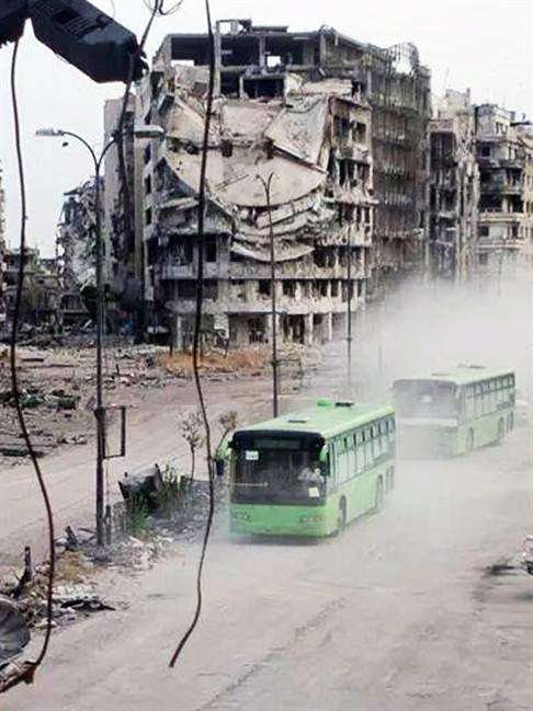 This Wednesday, May 7, 2014 photo provided by the anti-government activist group Coordination Committee of Khalidiya Neighborhood in Homs, which has been authenticated based on its contents and other AP reporting, shows buses carrying Free Syrian Army fighters leaving Homs, Syria. Exhausted and worn out from a year-long siege, hundreds of Syrian rebels on Wednesday left their last remaining bastions in the heart of the central city of Homs under a cease-fire deal with government forces. 