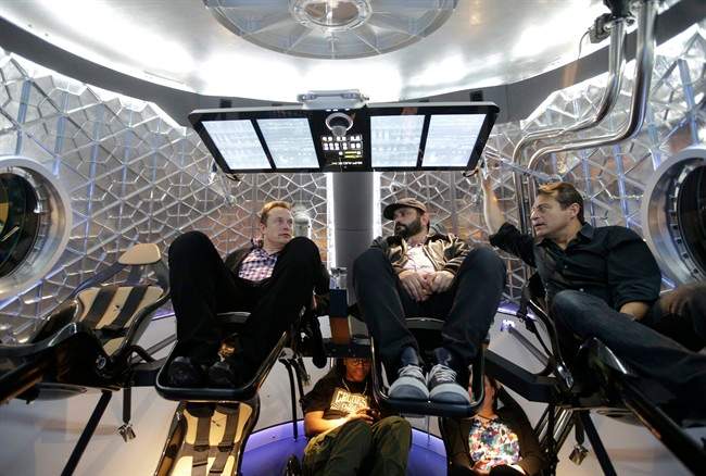 Elon Musk, left, CEO and CTO of SpaceX, mingles with invited guests inside the SpaceX Dragon V2 spaceship at the headquarters on Thursday, May 29, 2014, in Hawthorne, Calif. The V2 will be the new