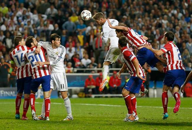 Real Madrid's Sergio Ramos, center, scores his side's first goal during the Champions League final soccer match against Atletico Madrid at the Luz Stadium in Lisbon, Portugal, Saturday, May 24, 2014. (AP Photo/Andres Kudacki).