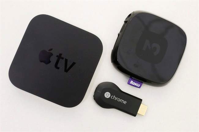 An Apple TV device, left, is shown alongside Google's Chromecast, center, and the Roku 2.