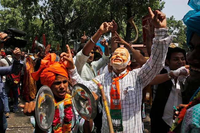 A Bharatiya Janata Party (BJP) supporter wears a mask Narendra Modi, India\’s next prime minister, and celebrates after preliminary results showed the BJP winning by a landslide, outside the party headquarter in New Delhi, India, Friday, May 16, 2014.