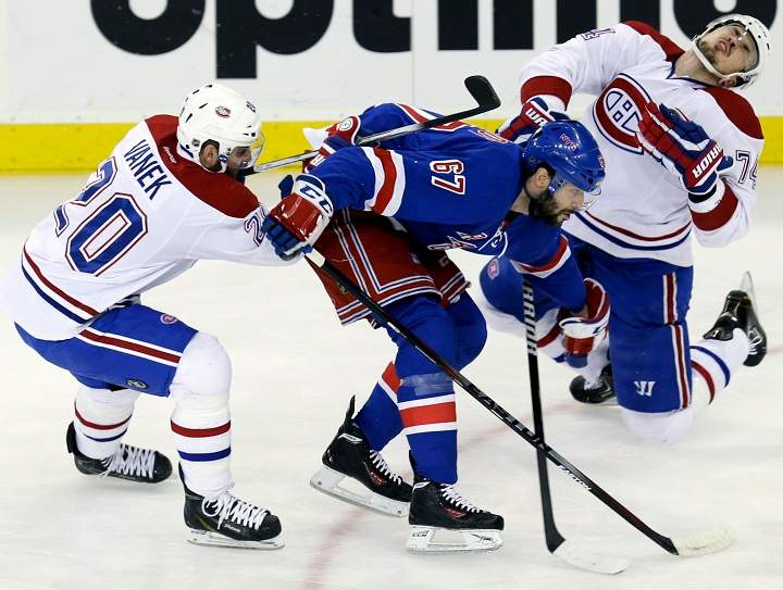 New York Rangers' Benoit Pouliot, center, commits a high sticking penalty against Montreal Canadiens' Alexei Emelin, right, while Thomas Vanek chases the puck during the first period of Game 4 of the NHL hockey Stanley Cup playoffs Eastern Conference finals, Sunday, May 25, 2014, in New York.