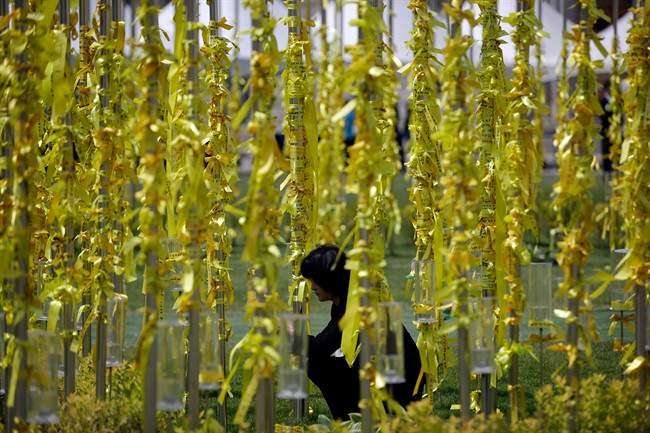 A woman attaches yellow ribbons for the victims and missing passengers of the sunken ferry Sewol at a group memorial altar in Seoul, South Korea, Wednesday, May 7, 2014. 