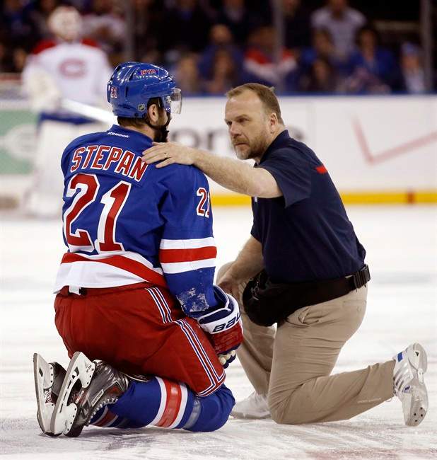In this May 22, 2014 photo, a staff member examines New York Rangers center Derek Stepan (21) after Stepan took a hit from Montreal Canadiens forward Brandon Prust during the first period of Game 3 of the NHL hockey Stanley Cup playoffs Eastern Conference finals in New York. (AP Photo/Kathy Willens).