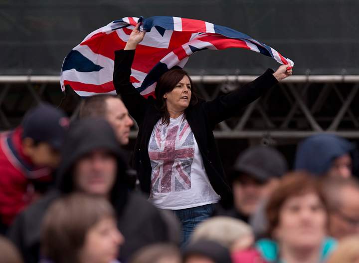 A royal watcher waves a Union Jack as Prince Charles and his wife Camilla, the Duchess of Cornwall, visit the Grand Parade in Halifax on Monday, May 19, 2014.
