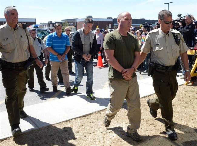 Former Montreal Maine and Atlantic Railway Ltd. employees Thomas Harding, right, Jean Demaitre, centre, and Richard Labrie are escorted by police to appear in court in Lac-Megantic, Que., on Tuesday, May 13, 2014.