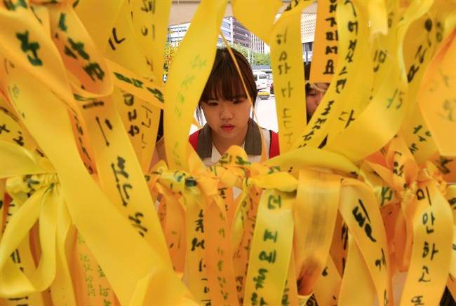 In this file photo, a high school student reads massages written on ribbons for the victims of the sunken ferry Sewol at a group memorial altar in Seoul, South Korea, Thursday, May 15, 2014. 